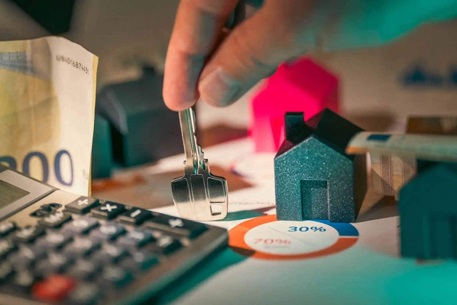Des mains annotent plusieurs devis d'assurance habitation avec une calculatrice et des pièces de monnaie